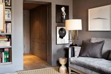 a stylish taupe living room with a grey sofa, built-in shelves, a glass coffee table and creamy leather poufs