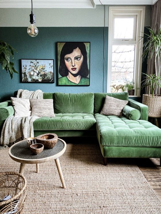 a whimsical living room with a blue accent wall, a green sectional, a jute rug, a coffee table, some art and potted plants