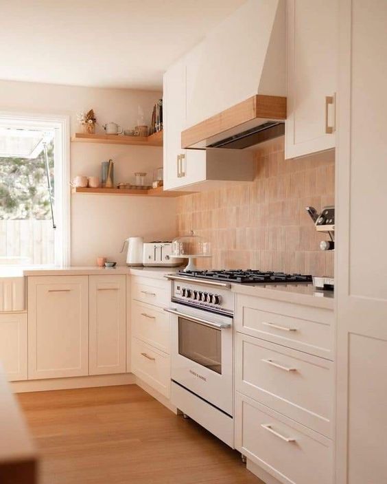 a white shaker style kitchen with a terracotta tile backsplash, white countertops and stained shelves and trim on the hood