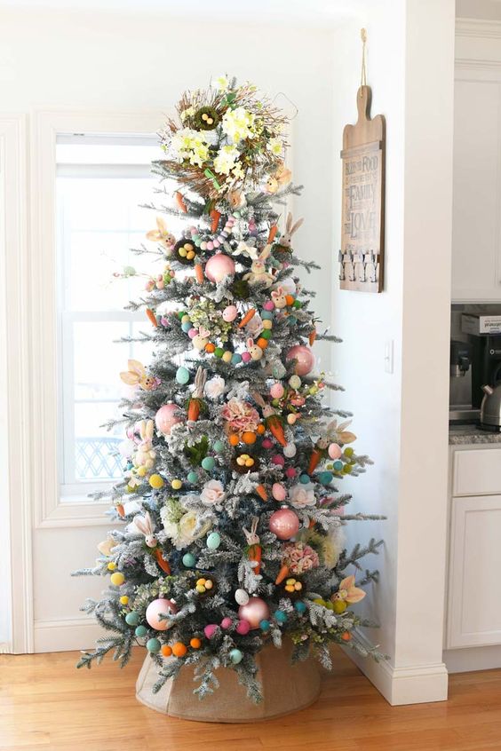 an Easter tree decorated with pastel pompoms, baubles, carrots, greenery and a spring wreath on top is amazing