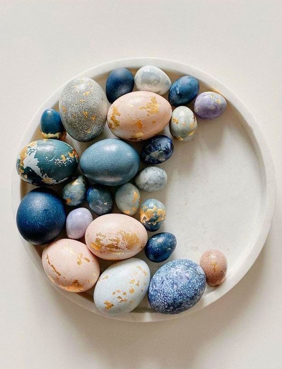 an arrangement of modern Easter eggs of pastel and blue shades, with gold foil of various shapes is amazing