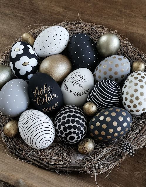 an arrangement of modern Easter eggs with polka dots, flowers, stripes and letters done in grey, black and gold