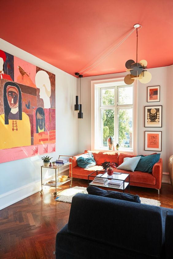 an extra bold living room with a red ceiling, a red sofa, bold art, a navy lvoeseat and some pendant lamps