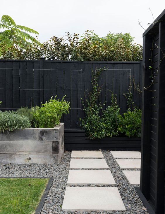 a black fence lined up with a raised garden bed with greenery is a stylish way to refresh the look of the outdoor space