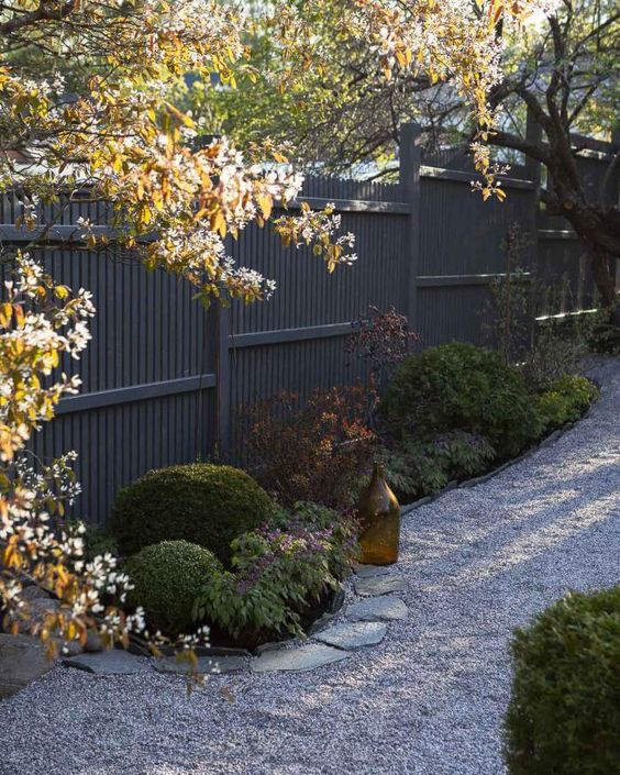 a black fence with a garden bed and some greenery are a lovely combo for a modern or even Zen-inspired garden