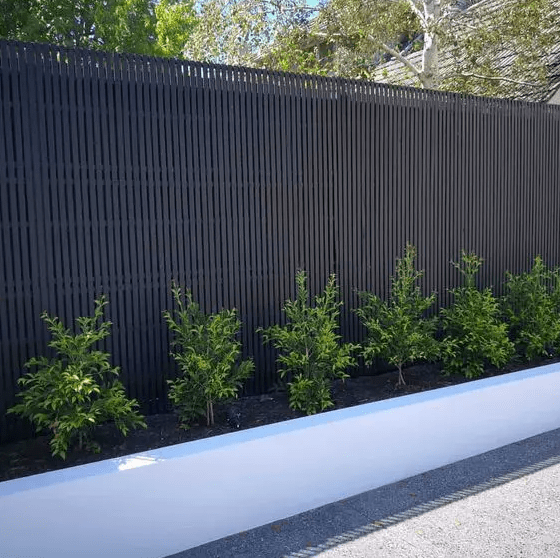 a black fence with a garden bed and some greenery are a stylish modern combo for a garden or a backyard