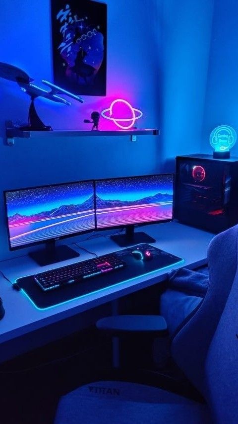 a blue and pink gaming corner with a shelf with decor, a poster, a PC with two screens, a desk and a chair plus some lit up devices