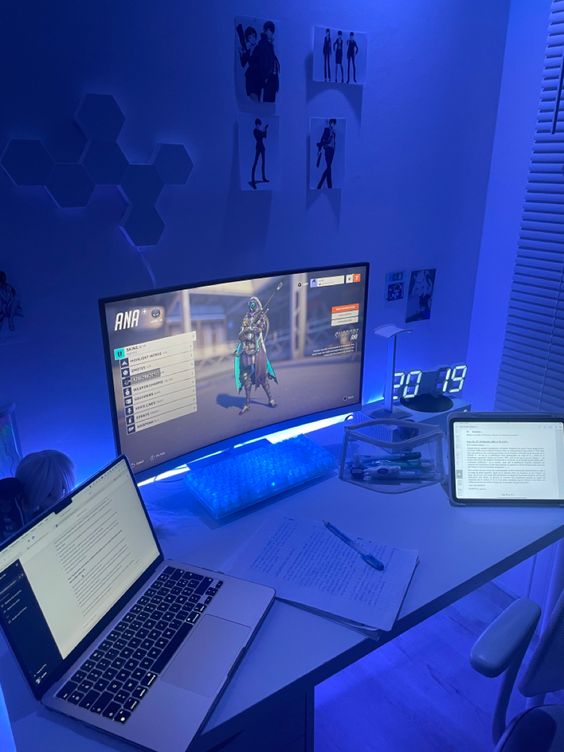 a blue gaming and studying setup with some devices, blue lights and clock, some chair and a desk is amazing