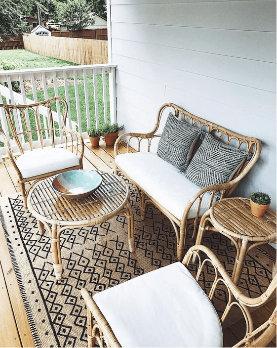 a boho porch with rattan furniture, neutral and printed textiles and potted greenery is a chic idea