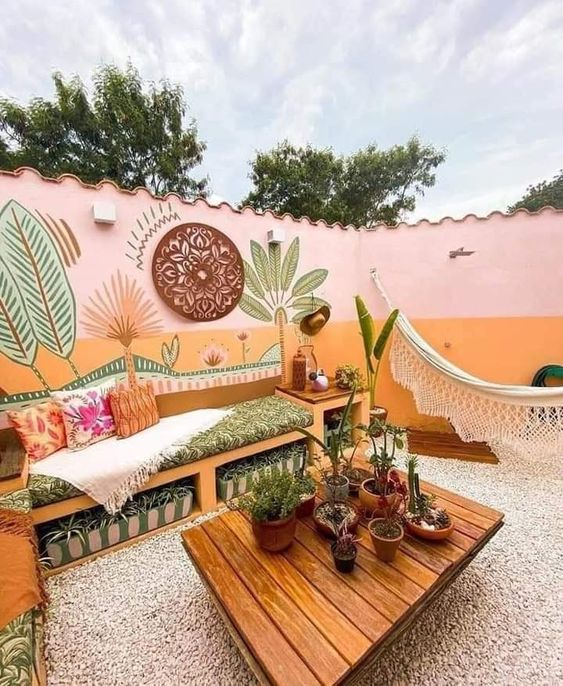 a bold boho tropical space with blush and orange walls, crate furniture, a coffee table, potted plants and bright decor