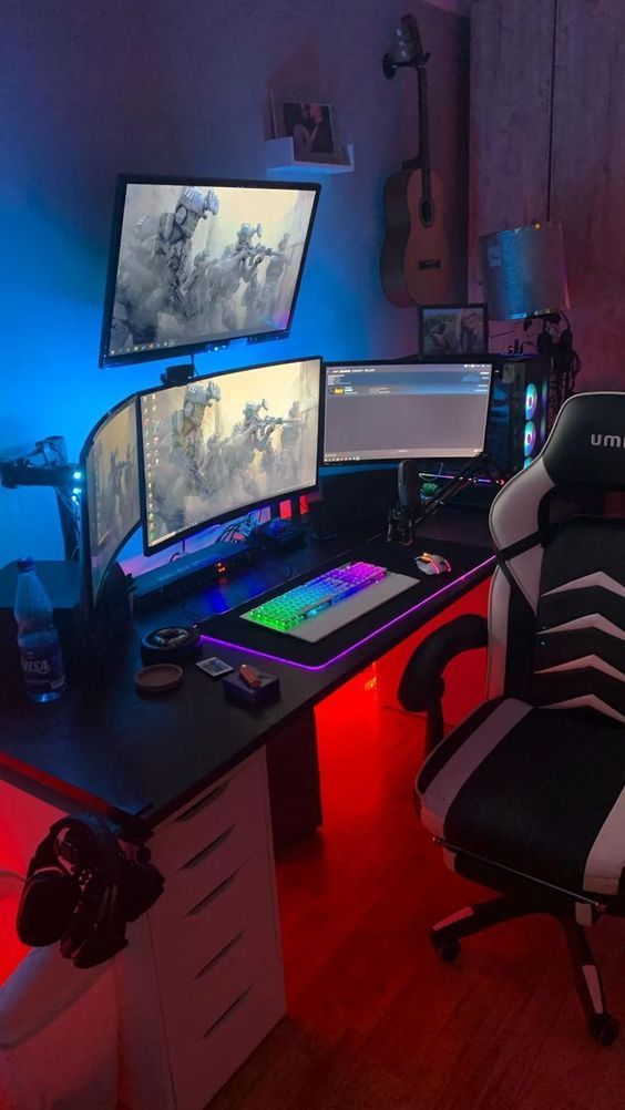 a bold gaming desk setup with several screens, a desk, a keyboard, a chair and some more devices plus blue light