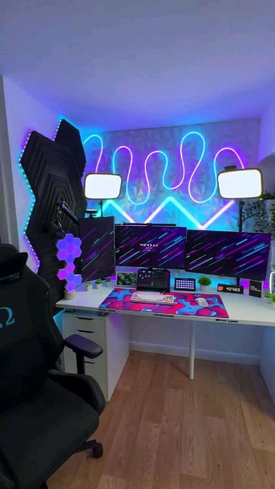 A bold gaming nook with colorful neon lights on the wall, sound proofing panels, a desk and some lamps over the space