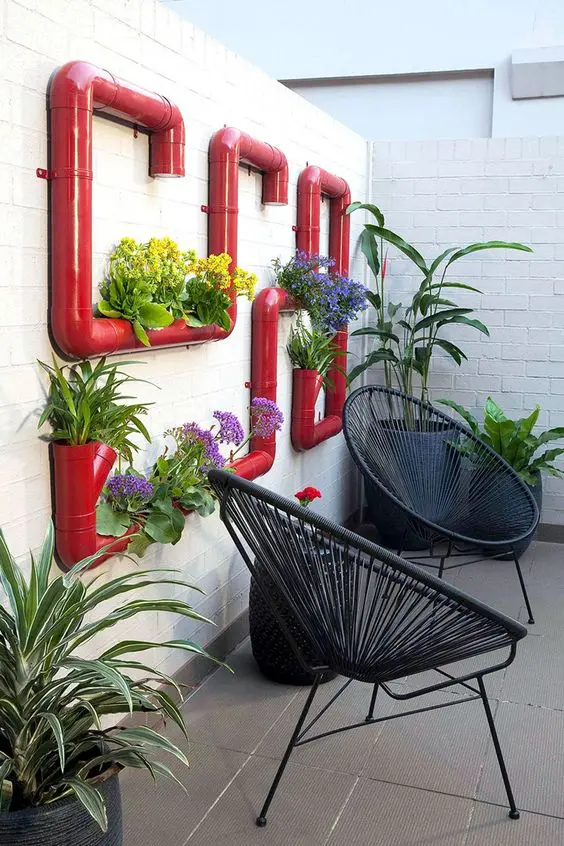 a bold red pipe garden on the wall, with bright blooms is a bright and cool decoration for any terrace, it looks very eye-catching