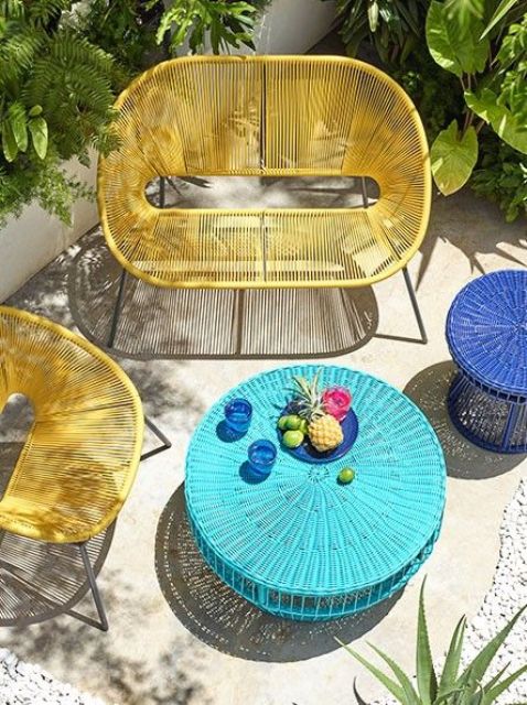 a bold summer terrace with a yellow chair and loveseat, a turquoise wicker table and a navy side table is amazing