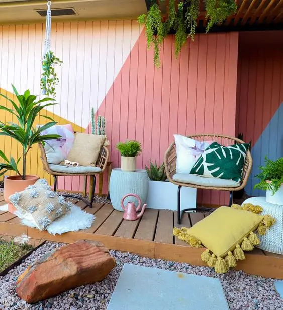 a bright space with a color block accent wall, rattan chairs, bright pillows, potted plants and some decor is cool