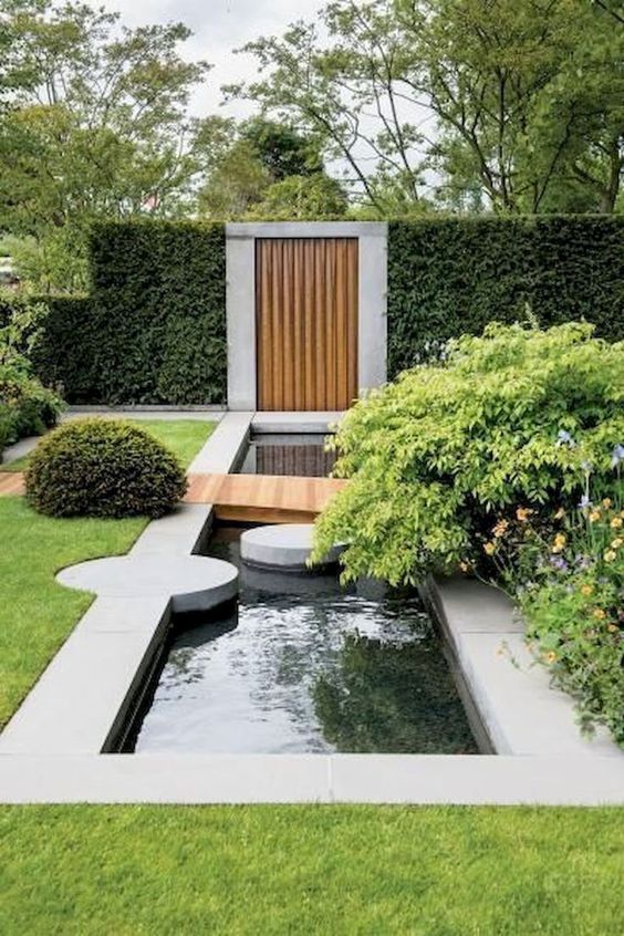 a chic modern garden with a water body, some greenery and blooms and a green lawn around is ultimate