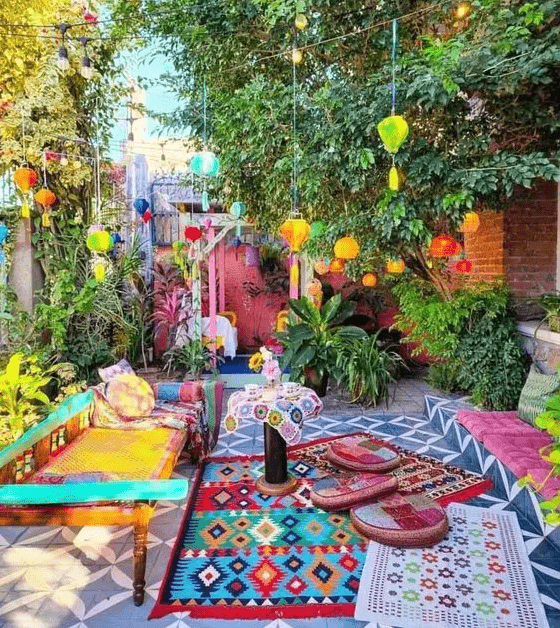 a colorful boho terrace with a woven daybed and colorful pillows and rugs, bright pendant lanterns with tassels