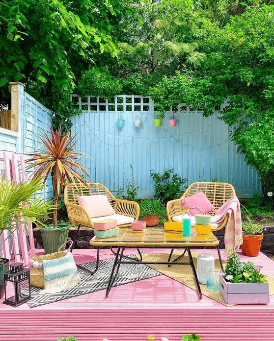 a colorful terrace with a pink deck, yellow chairs and a table, bright accessories and decor is really dopamine-infusing