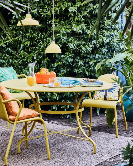 a colorful terrace with yellow furniture, bright pillows, pendant lamps and a jute rug is welcoming and cool