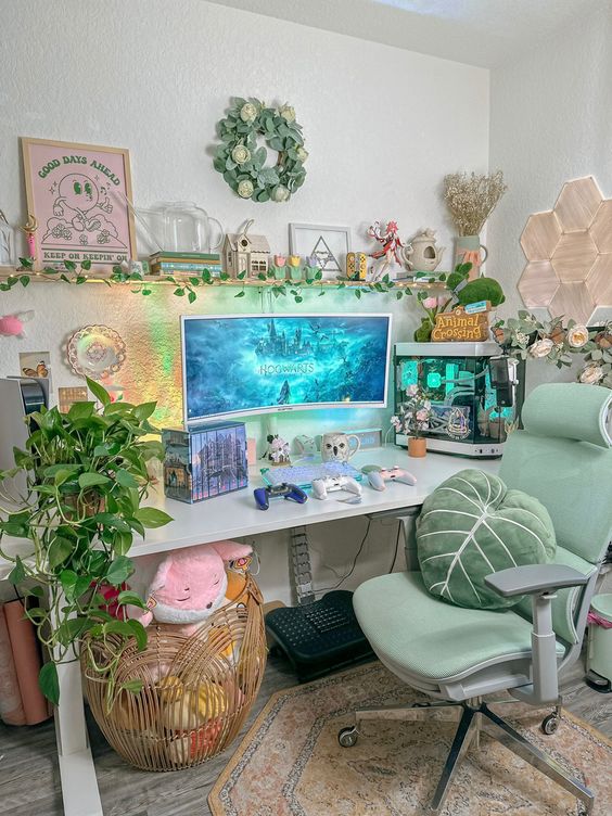 a cool gaming desk setup with a shelf with lovely decor, a desk with a PC, a green chair and a green leaf pillow, potted plants, a basket with plush toys and some wall decor