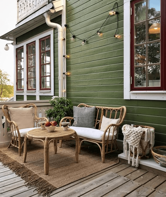 a cozy back porch with rattan furniture and a round table, with neutral upholstery, baskets and string lights is a lovely space