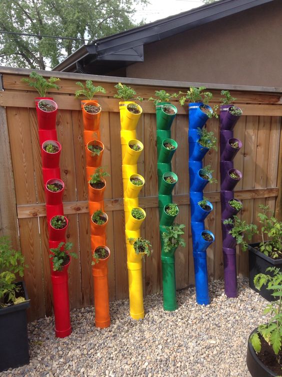 a creative rainbow vertical garden of pipes with planters is a cool and fun decor idea for any outdoor space