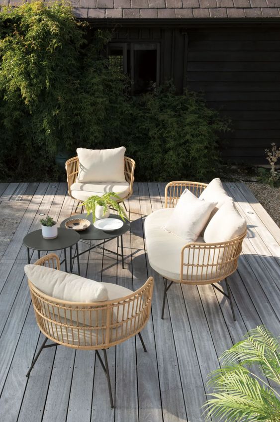 a deck with rattan chairs, neutral pillows and coffee tables plus greenery is great