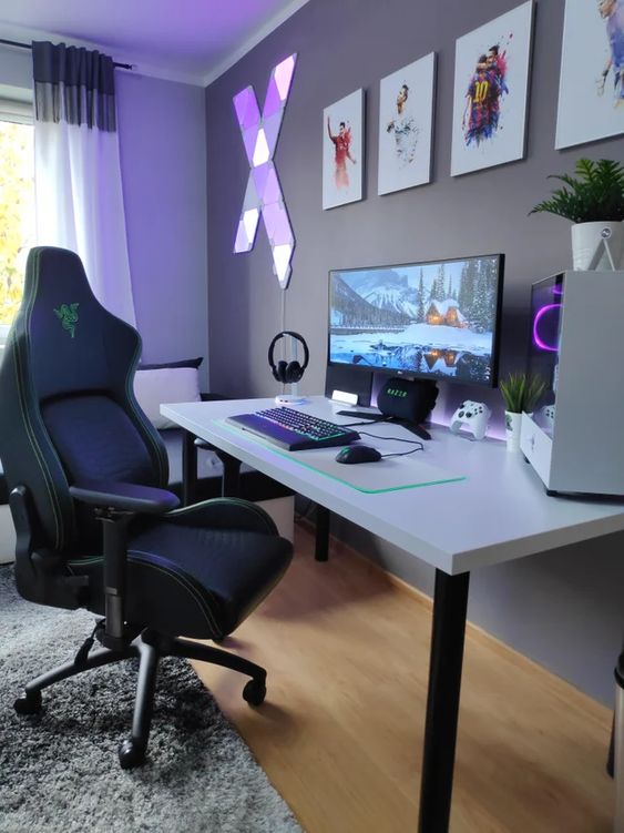 a delicate gamign desk setup with a Razer chair, a desk, a PC, a gallery wall and purple lights plus some devices