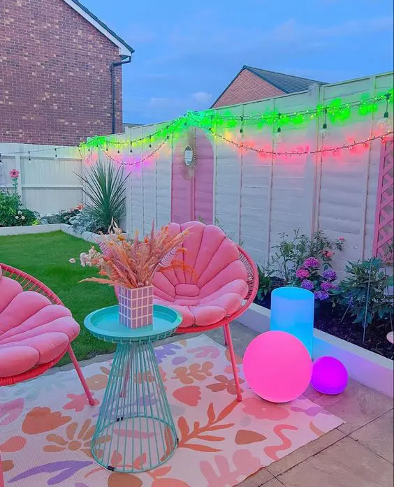 a dopamine decor terrace with bold neon lights, pink chairs, pink and blue neon lamps and a printed rug