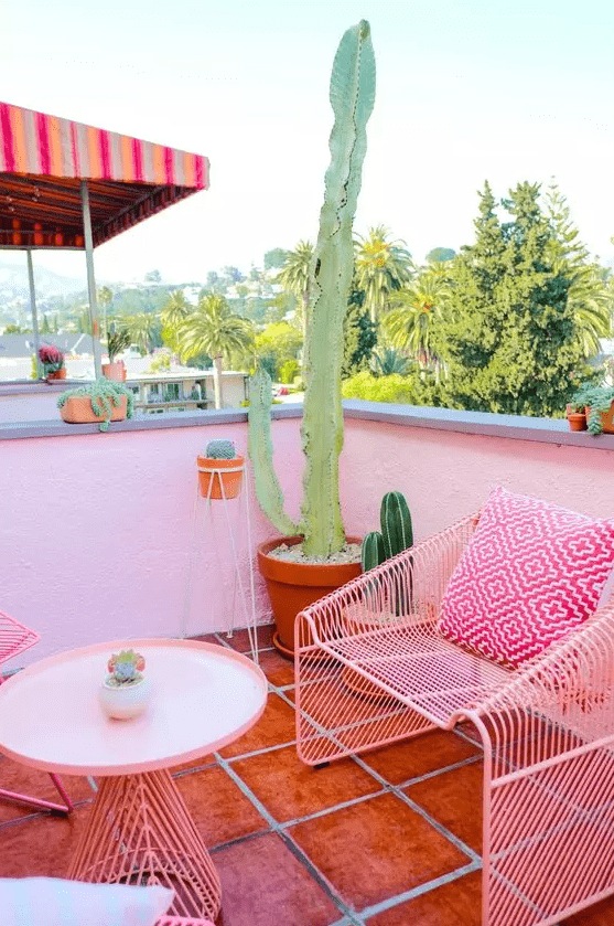 a hot pink terrace with forged furniture, potted cacti and bright pillows is a lovely and feminine space