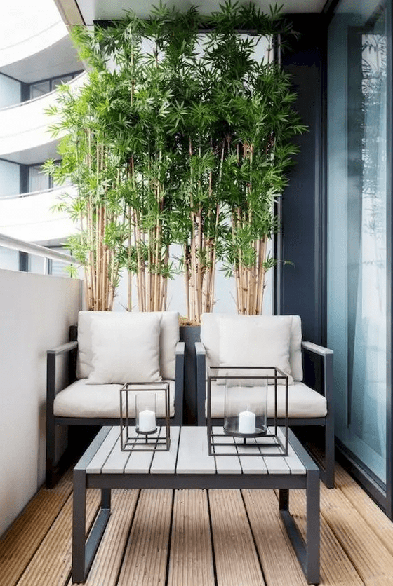 a laconic balcony in modern style, with bamboo, a couple of neutral chairs, a coffee table with candle lanterns is a cool idea