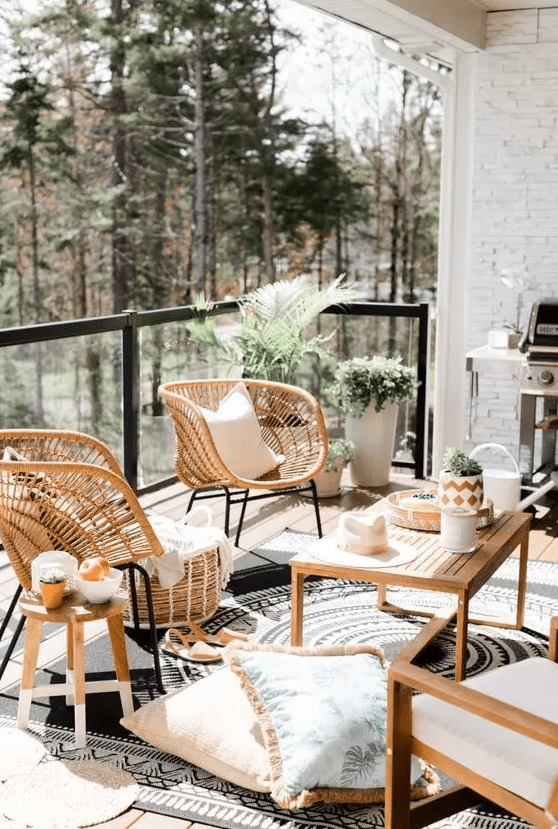 a lovely balcony with wooden and rattan furniture, with potted plants and greenery, with printed pillows and rugs is a cool space