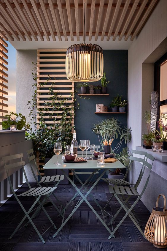 a modern dark balcony with green metal furniture, potted greenery, lanterns and lights is amazing