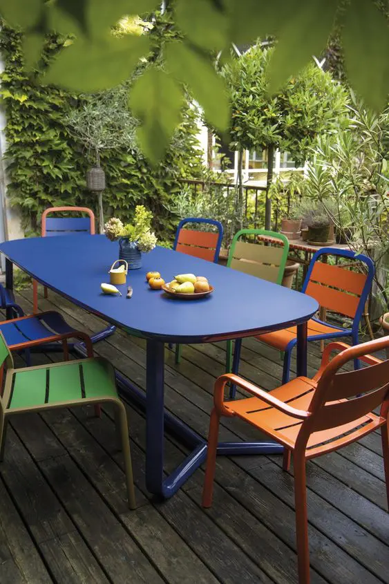 a modern dining space with a bold navy table, green, orange and yellow chairs is a catchy nook to have a meal