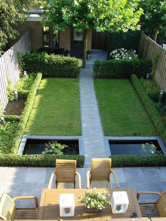 a modern garden with a green lawn and some shrubs plus blooms, a couple of ponds and a dining area with stained furniture