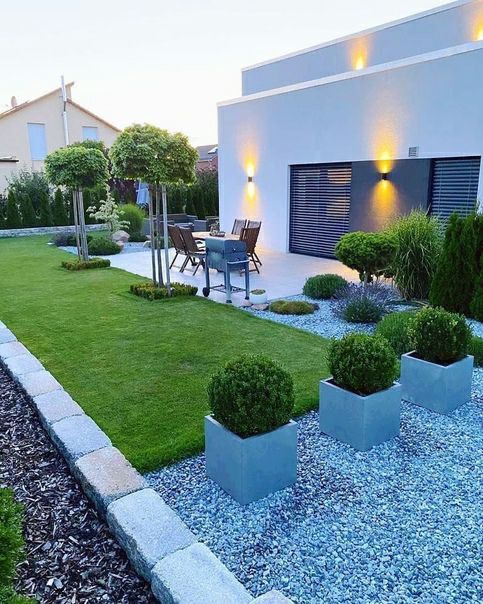 a modern garden with a green lawn, potted topiaries, trees, modern garden furniture and lights is amazing