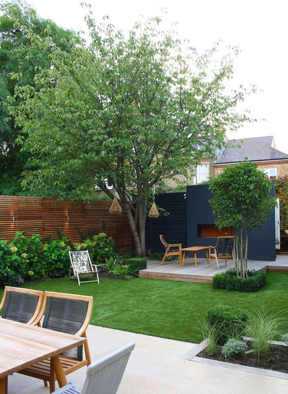 a modern garden with a green lawn, trees and shrubs, a deck with some modern furniture and a modern dining zone is cozy and cool