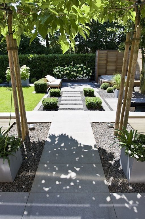 a modern garden with shrubs, blooms and trees plus neutral garden furniture is a lovely and cool space