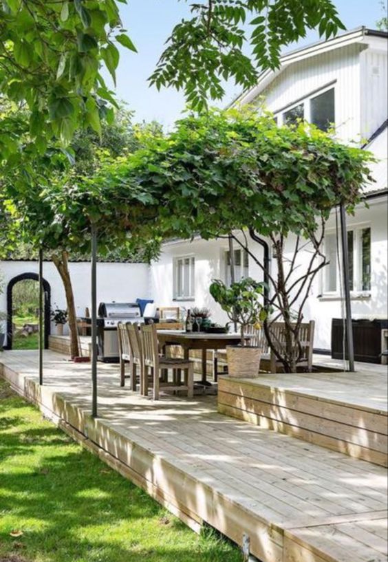 a modern multi-level outdoor space with a kitchen, a dining space and a green lawn is a chic and lovely space