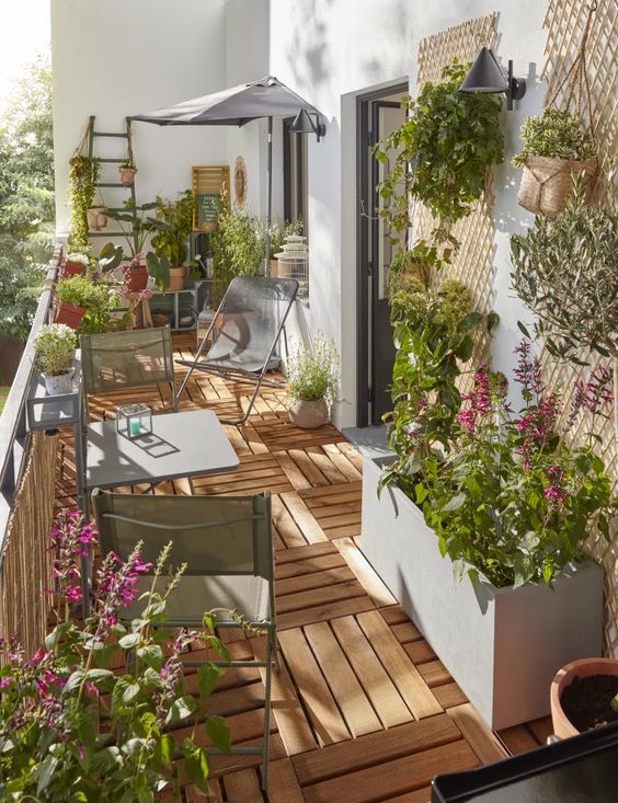 a modern neutral balcony with grey metal furniture, potted greenery and blooms, umbrellas and chairs