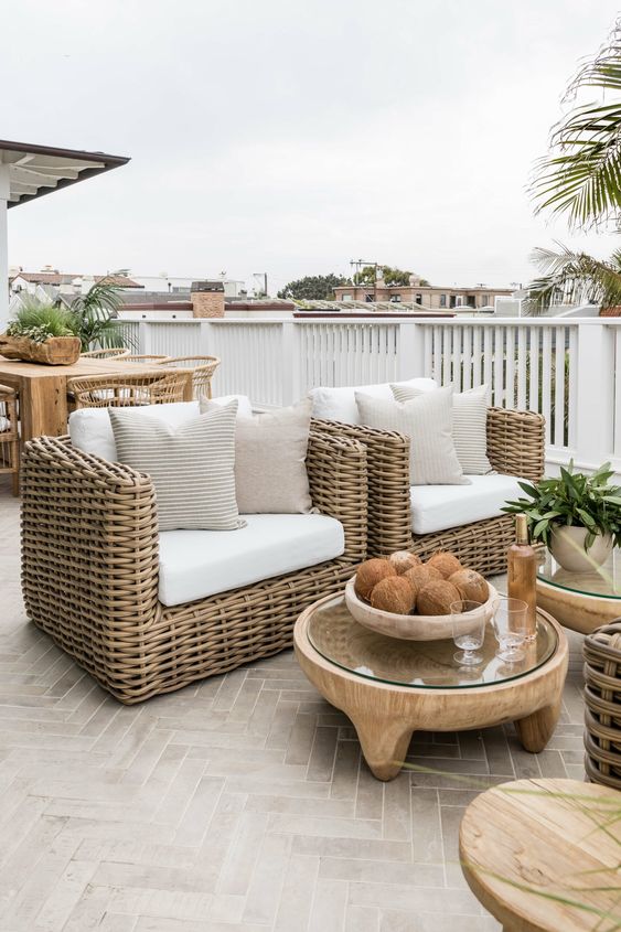 a modern terrace with wicker furniture, wooden tables, greenery and decor is very chic and cool