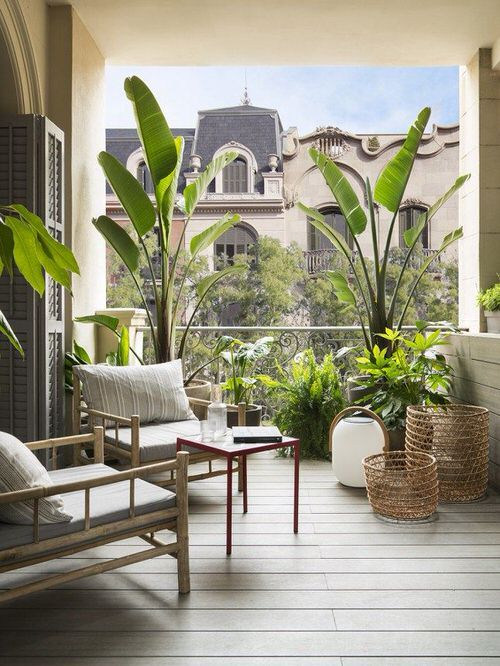 a modern tropical balcony with neutral seating furniture, baskets and lanterns and potted greenery