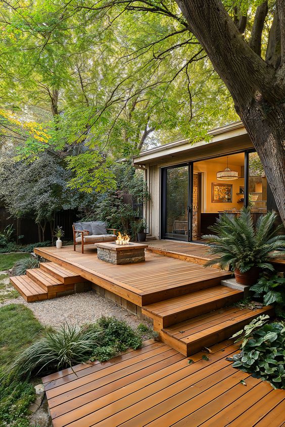 a multi-level deck with a sofa, a fire pit, decks and greenery plus trees around is very cozy