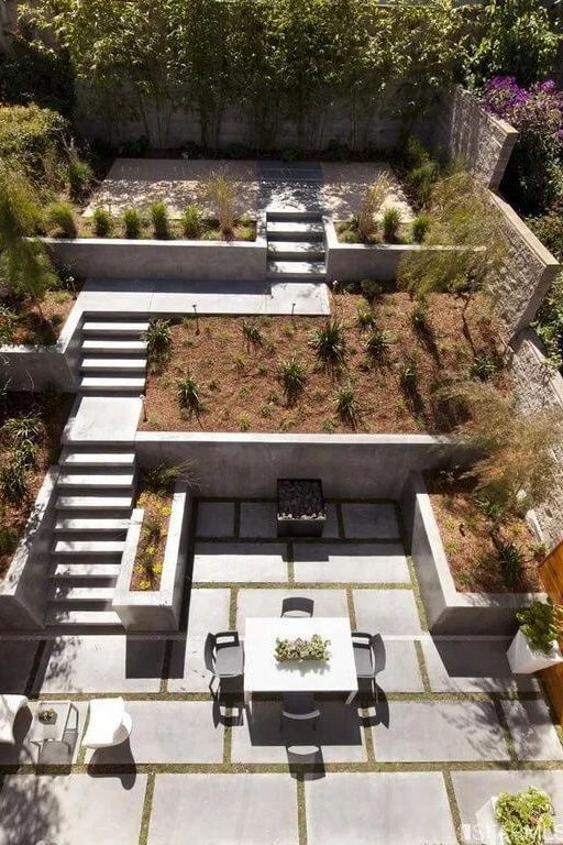 a multi-level outdoor space with a terrace, some raised garden beds, a dining zone and some plants