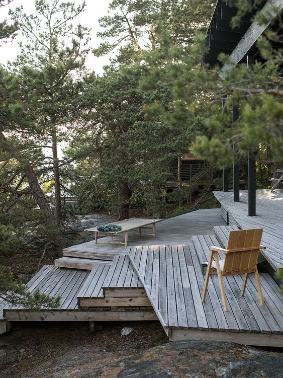 a multi-level outdoor space with reclaimed decks, modern furniture and trees around is a cool space to have a rest in