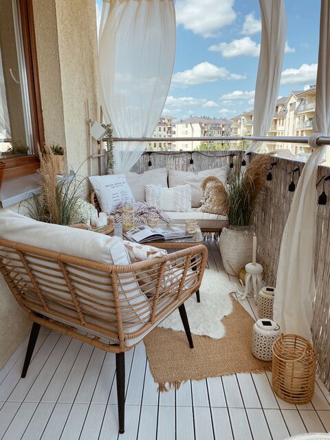 a neutral boho balcony with rattan furniture, grasses in vases, lanterns and neutral textiles