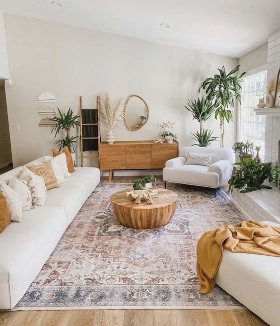a neutral boho living room with creamy seating furniture, a boho rug, a coffee table and some potted plants