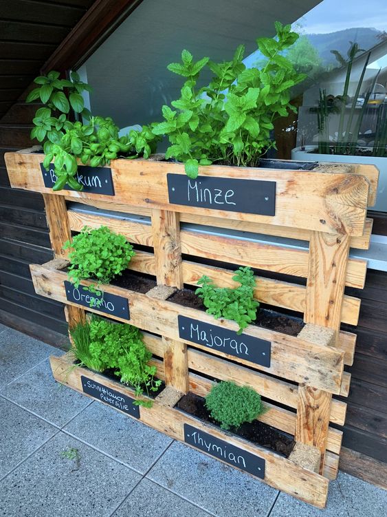 a pallet vertical garden with herbs and chalkboard stickers is a stylish idea for a rustic or Scandinavian balcony