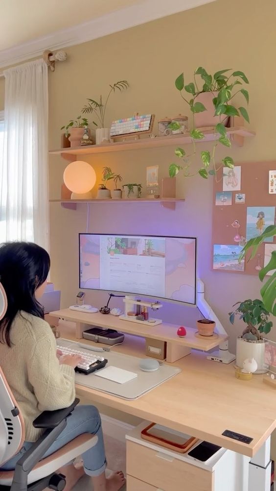 a pretty gaming desk setup with a desk, a raised stand with a monitor, potted plants, a lamp and a memo board is amazing