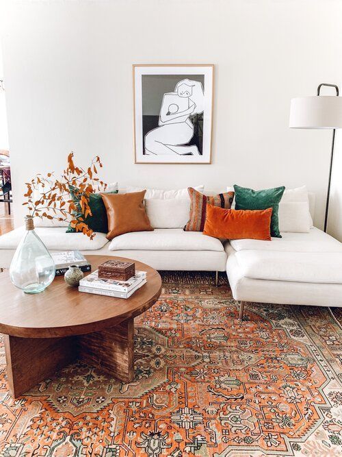 a pretty living room with a white sectional and colorful pillows, a boho rug, a coffee table, some decor and a floor lamp